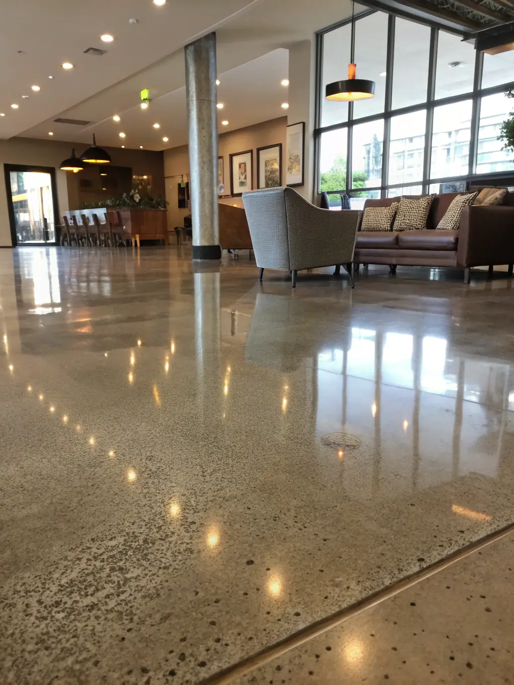 A wide shot of a polished concrete floor in a modern loft, reflecting natural light and showcasing its sleek, shiny finish and minimalist aesthetic.